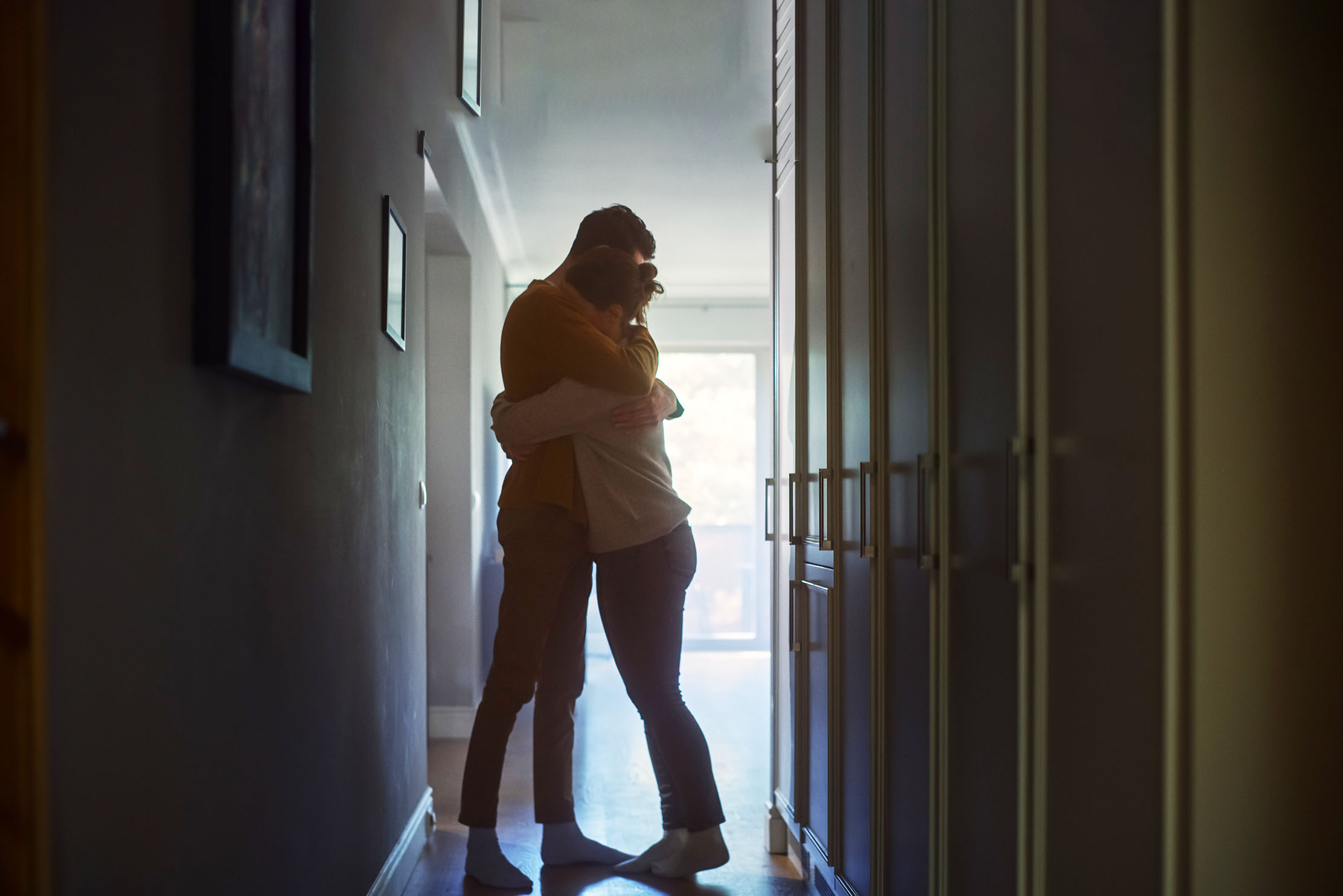 A couple hug each other in the hallway of a house