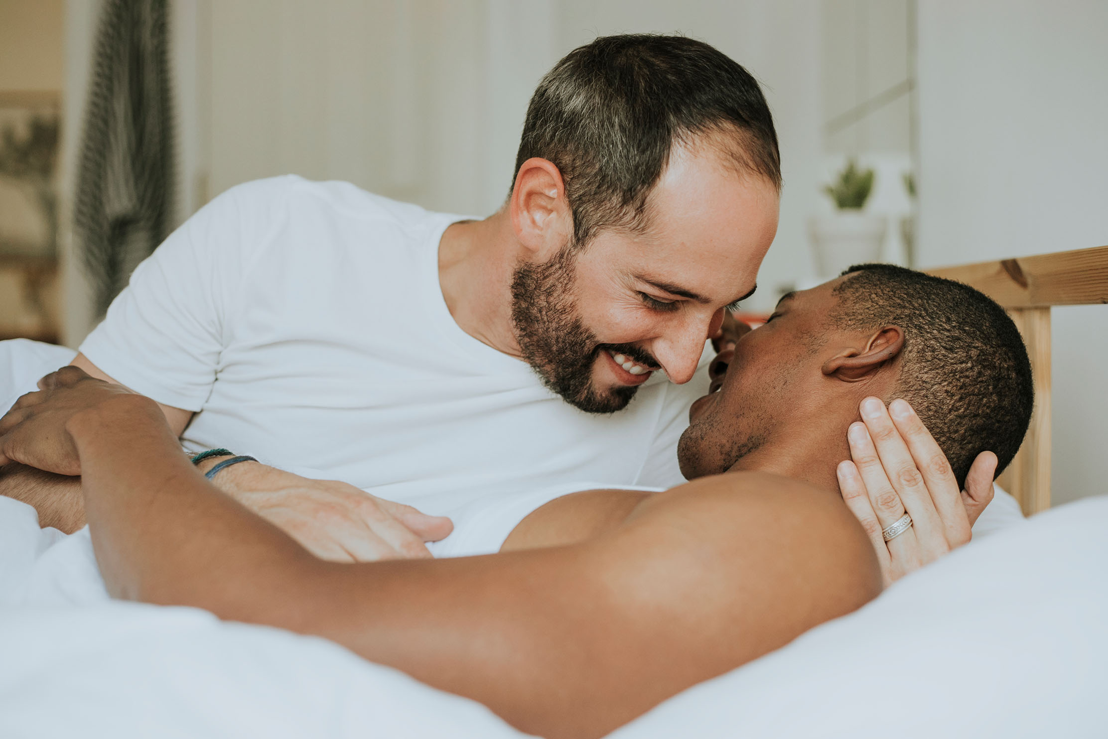 A mixed race couple laughing together in bed