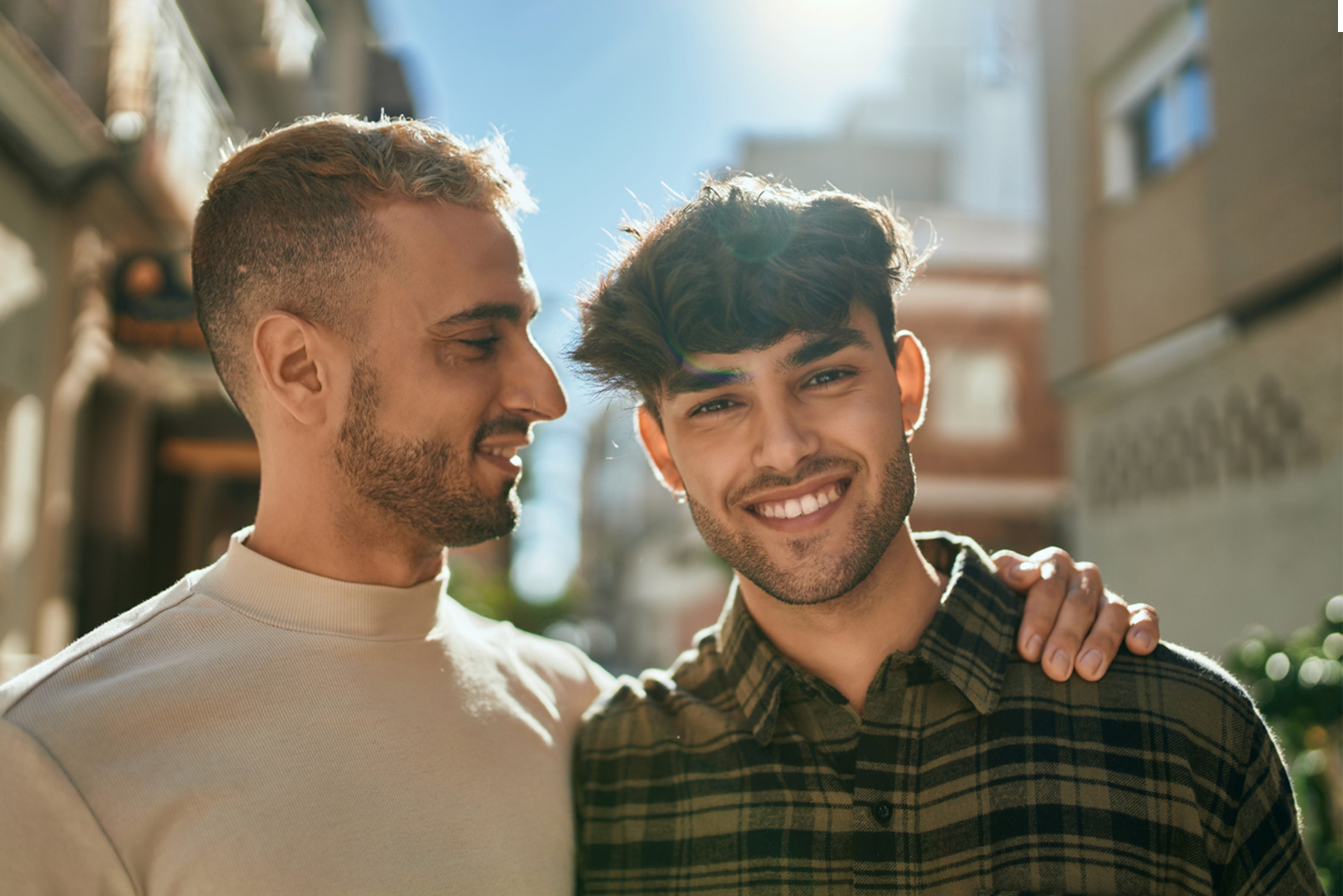 A gay couple smile in the sun