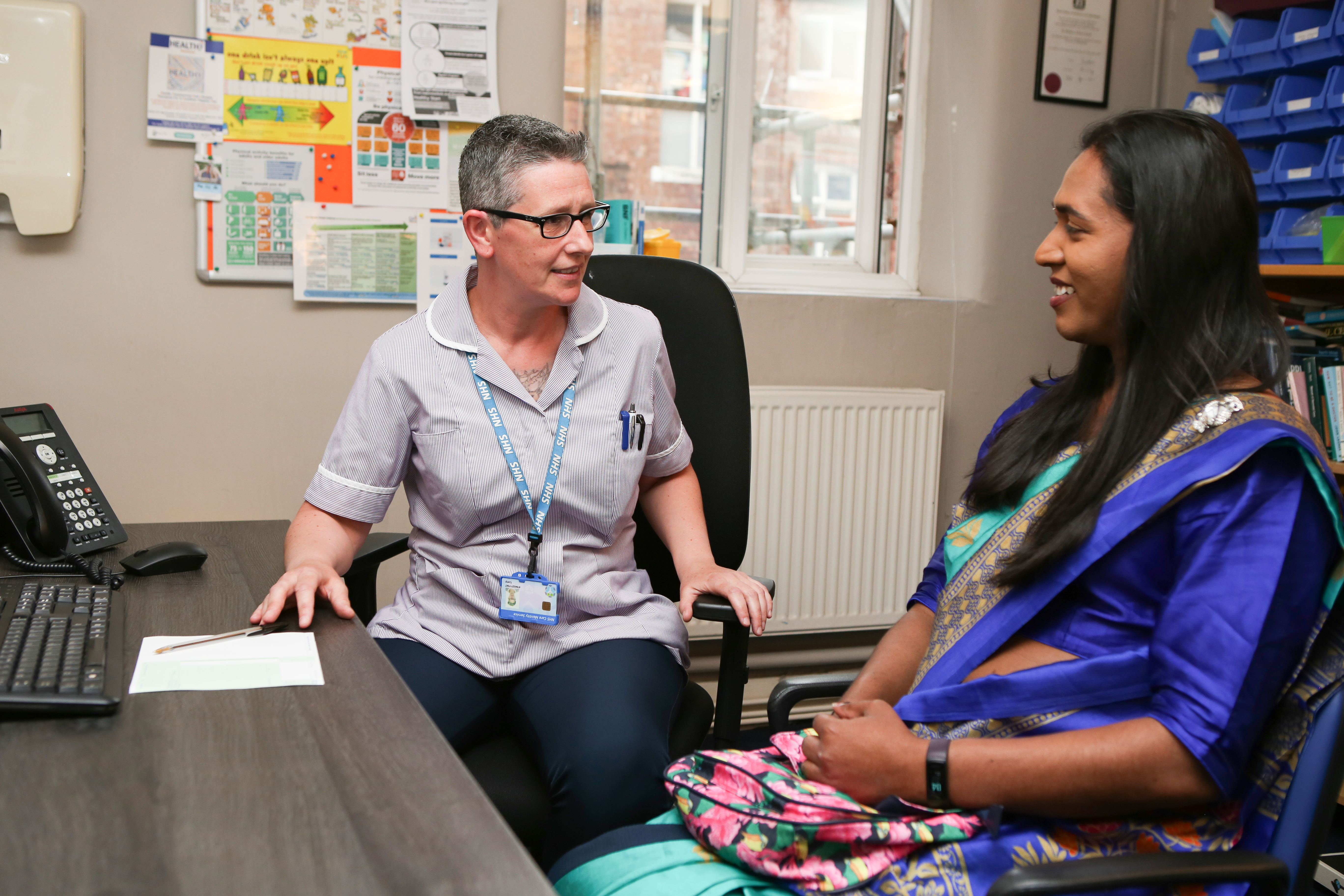 woman in a sari speaking to a nurse in a clinic